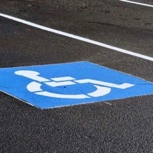 Close-up of a blue and white handicapped parking symbol painted on asphalt in a private business lot