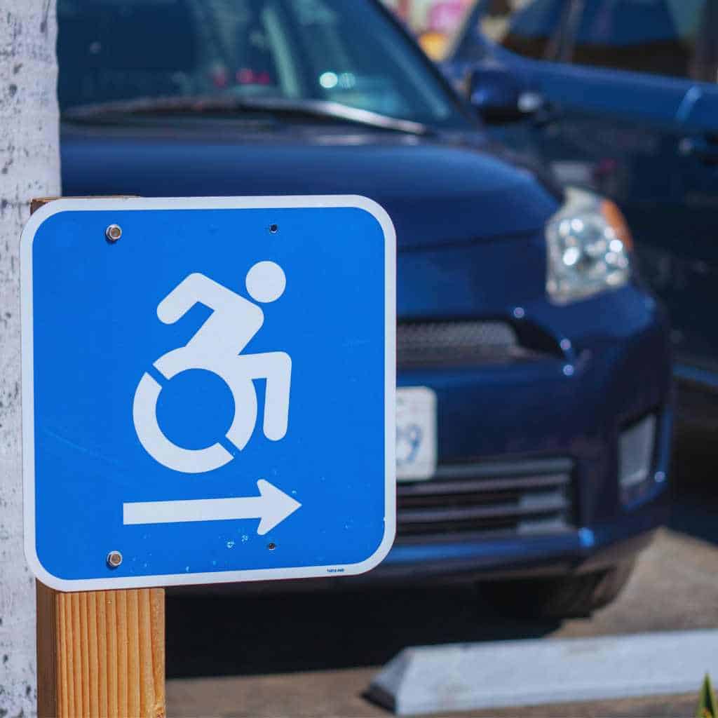 Blue dynamic accessibility sign with arrow pointing toward ADA-compliant parking in California lot