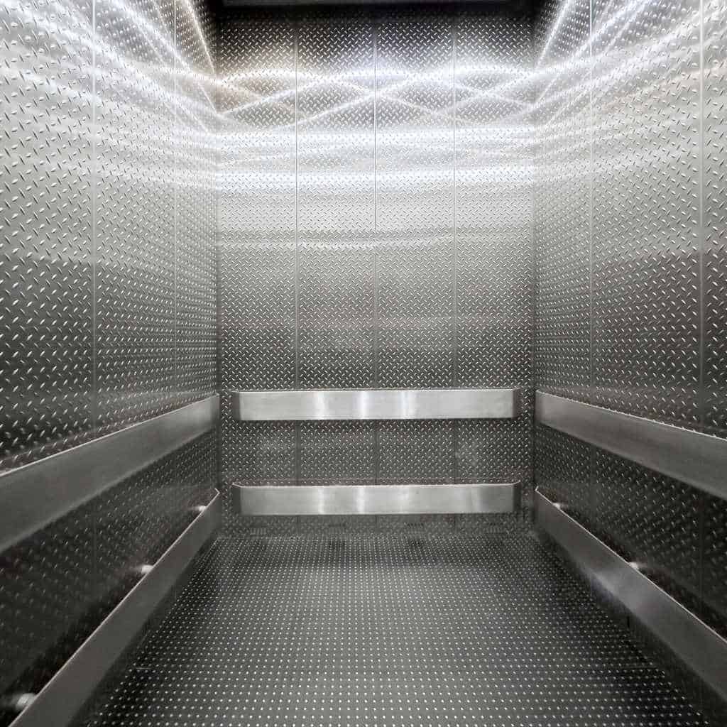 ADA-friendly elevator interior with wide clear floor space and protective handrails suitable for wheelchair users in a California commercial building.