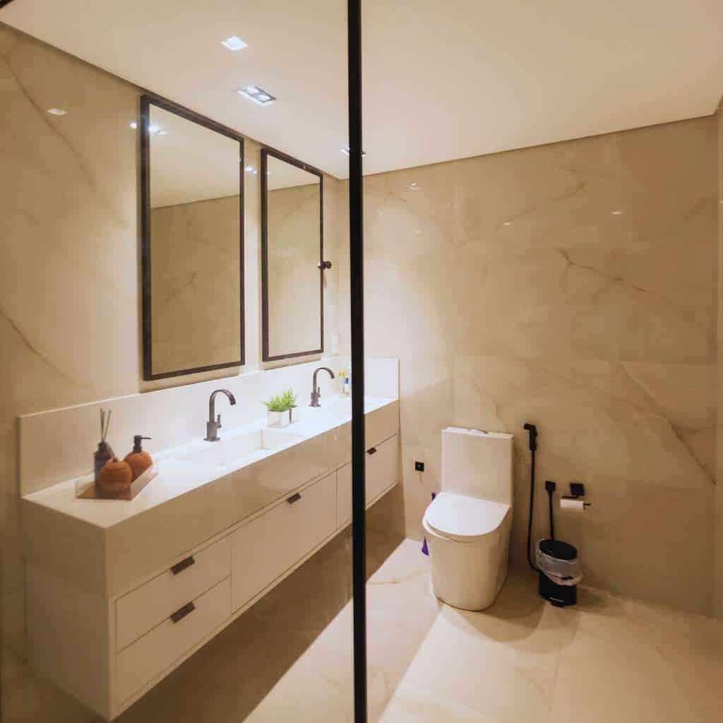 Modern restroom with dual sinks and a wall-mounted mirror, but no required grab bars, accessible clear floor space, or compliant toilet and lavatory dimensions under ADA and California Title 24 standards.
